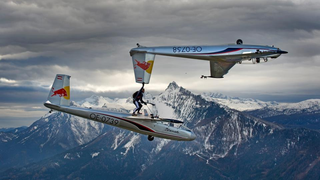 Amazing video of a man holding a glider while flying on another glider